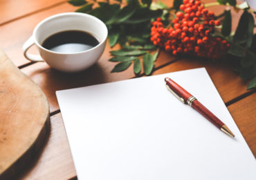 a cup of coffee, pen and paper and red flowers on a table (How to Handle Overseas Assets in Your Will_Asia_Law_Network)