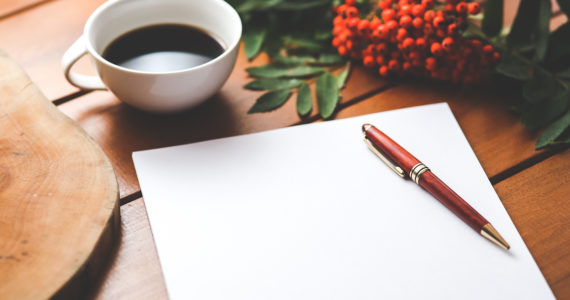 a cup of coffee, pen and paper and red flowers on a table (How to Handle Overseas Assets in Your Will_Asia_Law_Network)