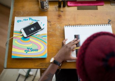 a man drawing on paper with a ruler on it. left of table has an iphone on a book by Dr Seuss (copyright_law_singapore_asia_law_network)