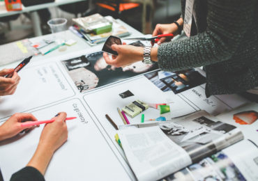 people working together on a table top with pens and magazine on it (registered design act singapore)