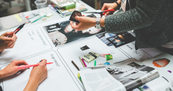 people working together on a table top with pens and magazine on it (registered design act singapore)