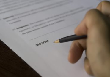 person holding a pen preparing to sign an agreement employment_contract_asia_law_network
