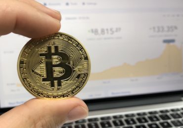 bitcoin against a laptop of stocks charts (Cryptocurrency)
