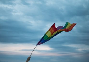 a hand holding the rainbow flag (LGBT Couple Singapore_Asia_Law_Network)