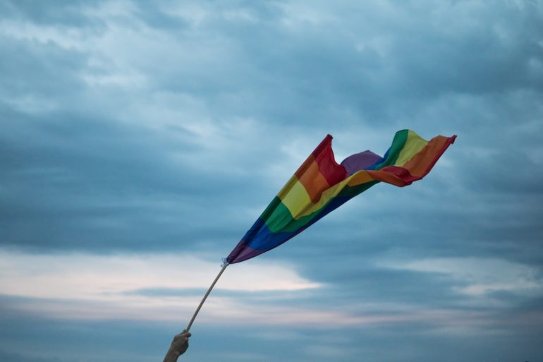 a hand holding the rainbow flag (LGBT Couple Singapore_Asia_Law_Network)