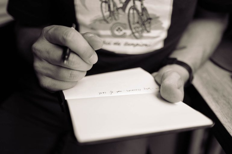 a person holding a pen and writing on a notebook (mental_capacity_act_asia_law_network)
