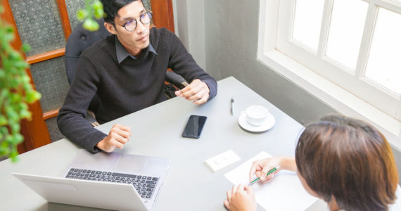 man with laoptop and a woman having a discussion (Here are the legal considerations of starting a tech startup in Singapore)