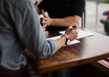 2 man having a discussion at a wooden table (mediation_singapore_asia_law_network)