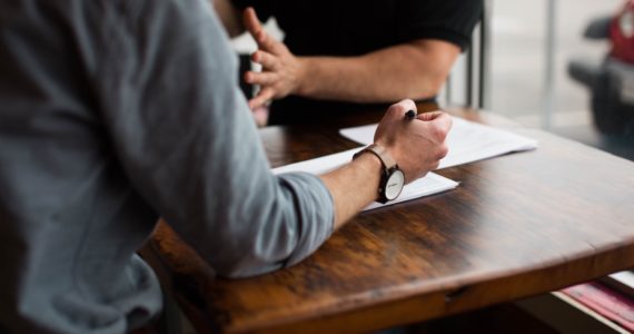 2 man having a discussion at a wooden table (mediation_singapore_asia_law_network)