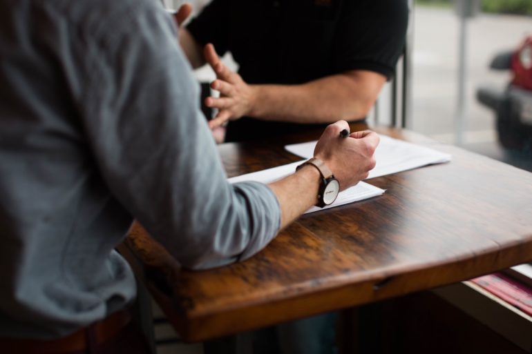 2 man having a discussion at a wooden table (mediation_singapore_asia_law_network)