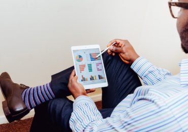 a man with a tablet looking at graphs and charts (What Is Series Funding & Why You Need To Know Your ABCs_Asia_Law_Network)