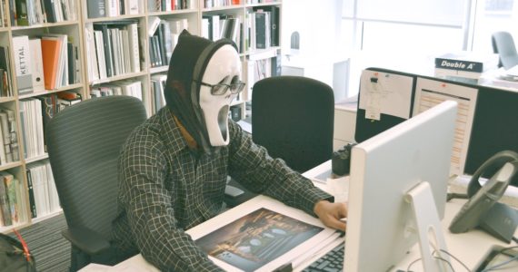 man wearing a white mask using the computer with a bookcase in the background white_collar_crime_asia_law_network